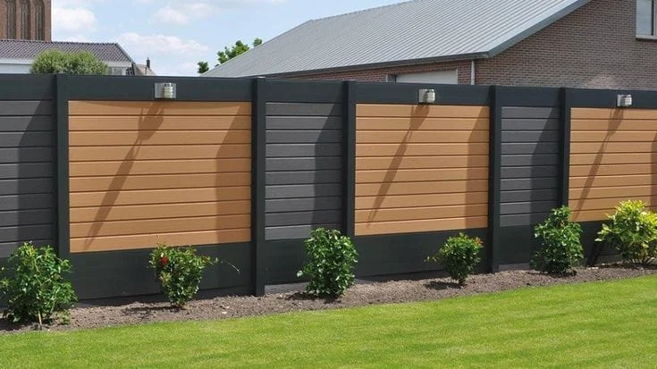 Een stijlvolle Verasol aluminium schutting met houtlook panelen in bruin en antraciet, geplaatst in een moderne tuin met een strak gazon en groene beplanting.