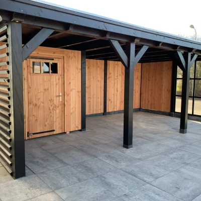 Moderne houten blokhut met overkapping, uitgevoerd in zwart en natuurlijk hout. Voorzien van een afgesloten berging met houten deur en een ruime overdekte zitplek. Ideaal als tuinhuis met overkapping voor extra opslag of een sfeervolle loungehoek.